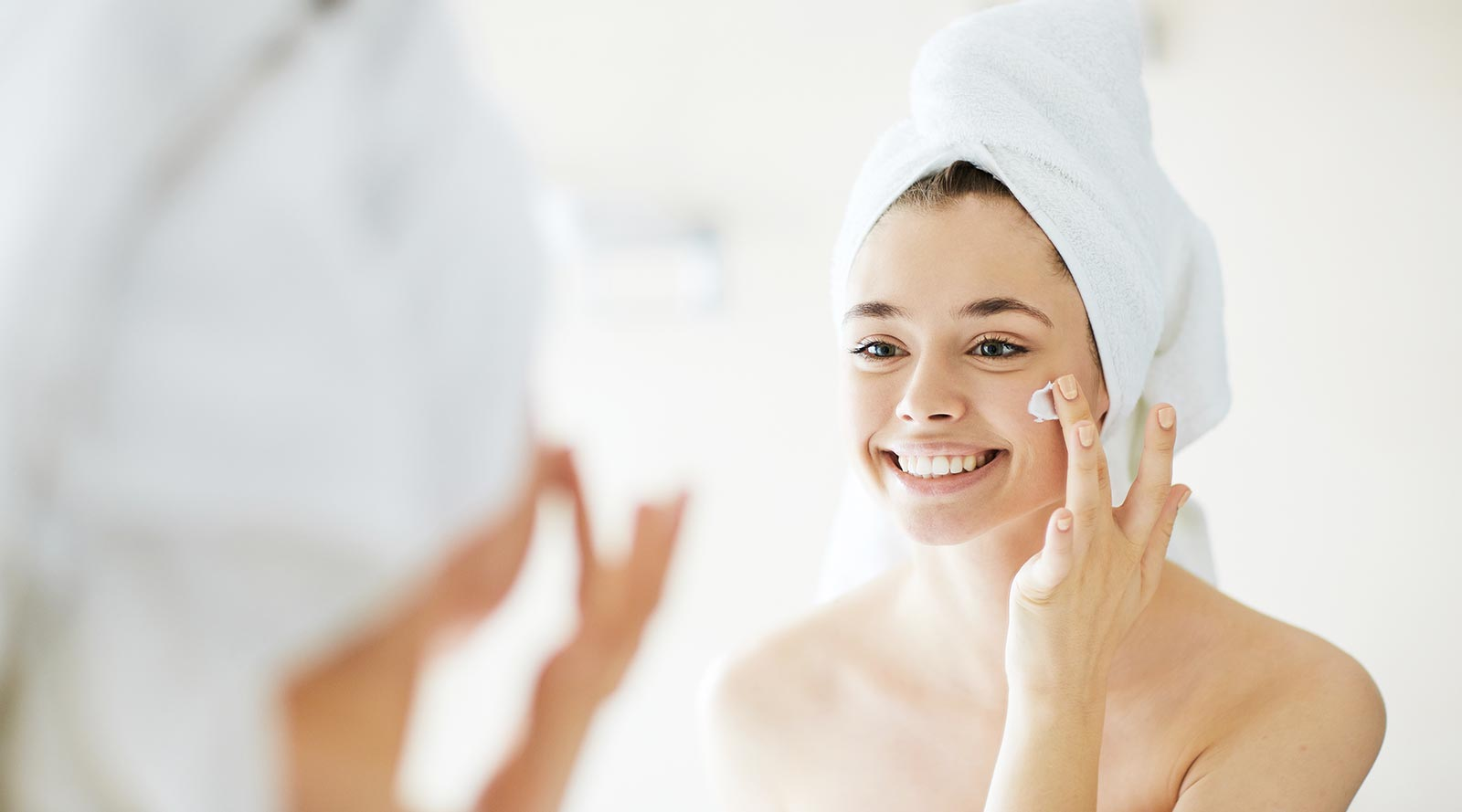 Woman applying luxury lotion to left shoulder for soft and smooth skin.